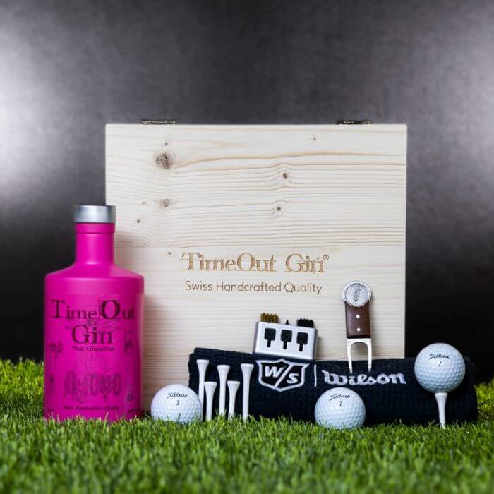 TimeOut Gin Geschenkbox mit Golf-Accessoires auf grünem Rasen, ideal für Golfliebhaber und Genussfreunde.